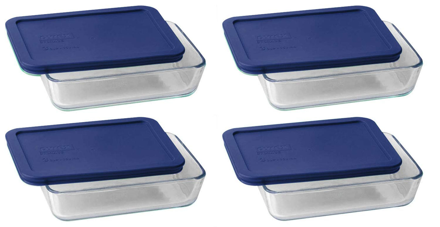 Set of four glass food storage containers with blue lids on a white background