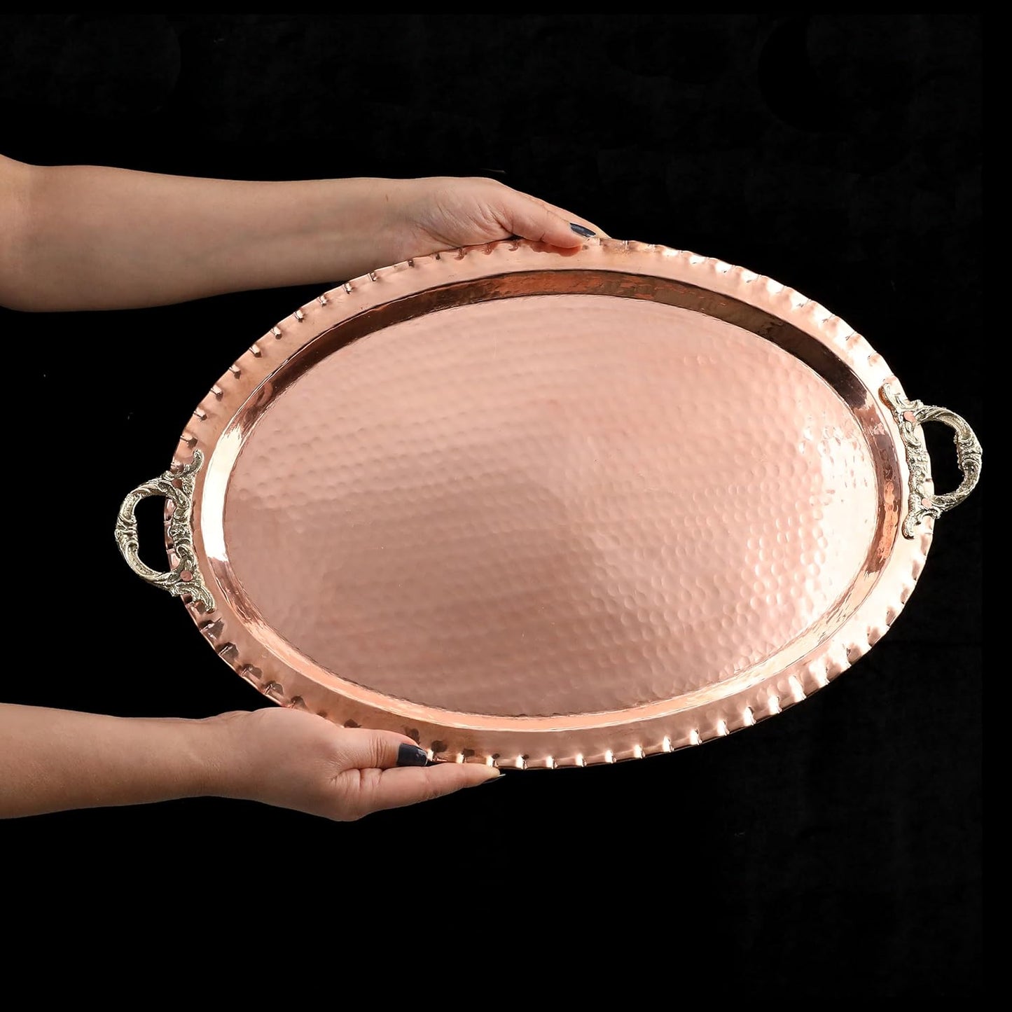 Copper tray held by a person against a black background