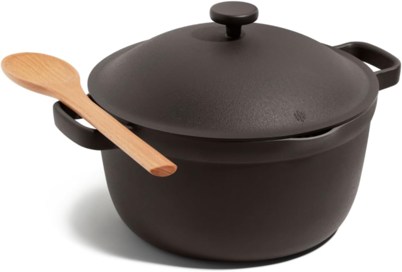 Black cast iron pot with wooden spoon on a white background