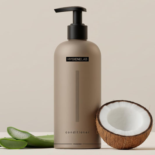 Beige conditioner bottle with black pump, Hygienelab label, coconut, and aloe vera leaves on a beige background
