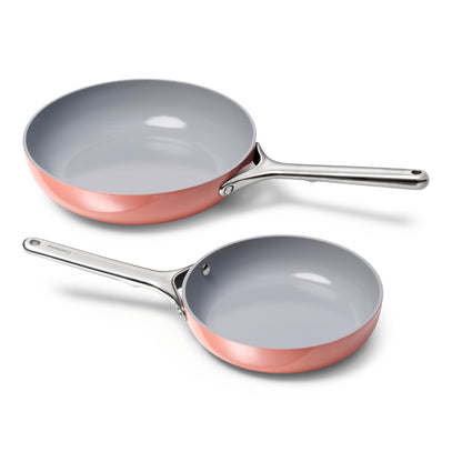 Two ceramic cookware pans with copper trim on a white background