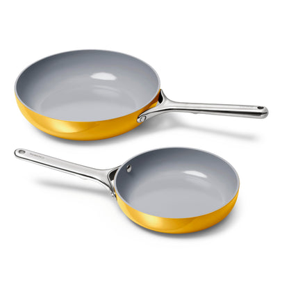 Two frying pans with gold trim and silver handles on a white background