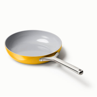Frying pan with yellow exterior and gray interior on a white background