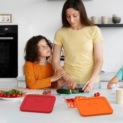 Woman and child preparing vegetables in a kitchen with colorful cutting boards.