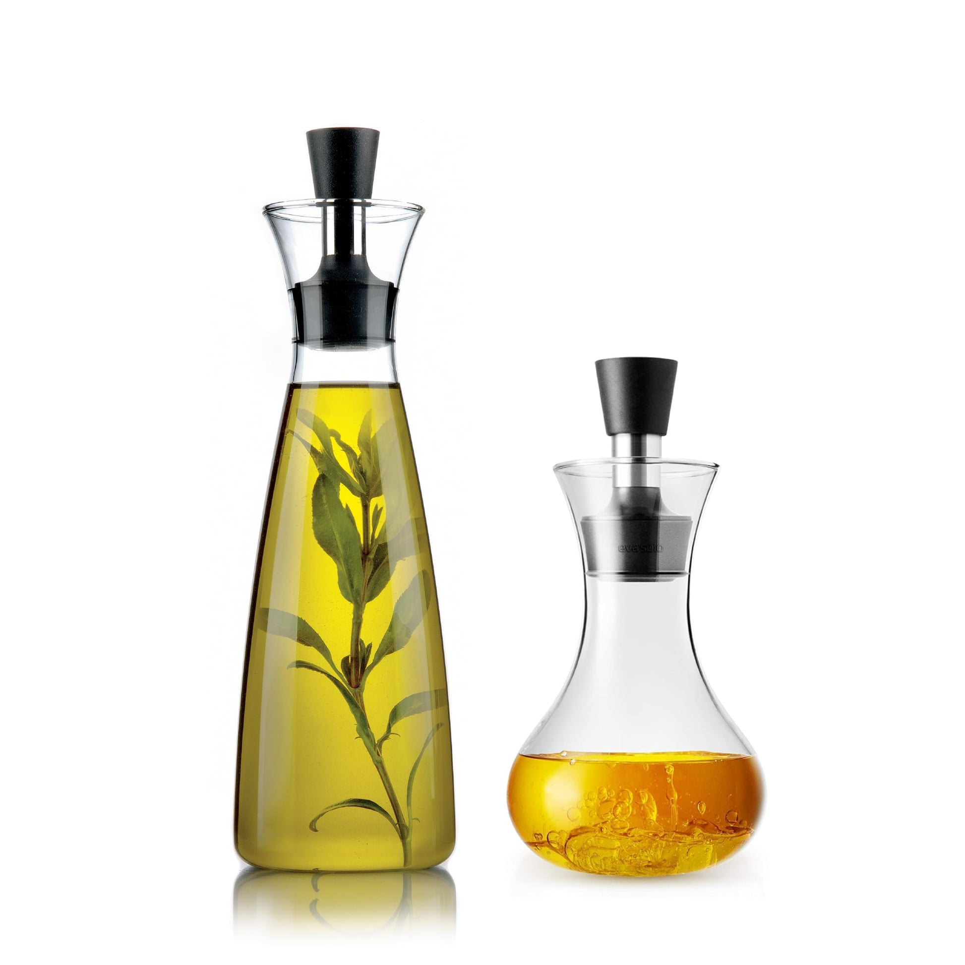 Eva solo oil vinegar carafe with black caps, one containing a branch of leaves, on a white background.