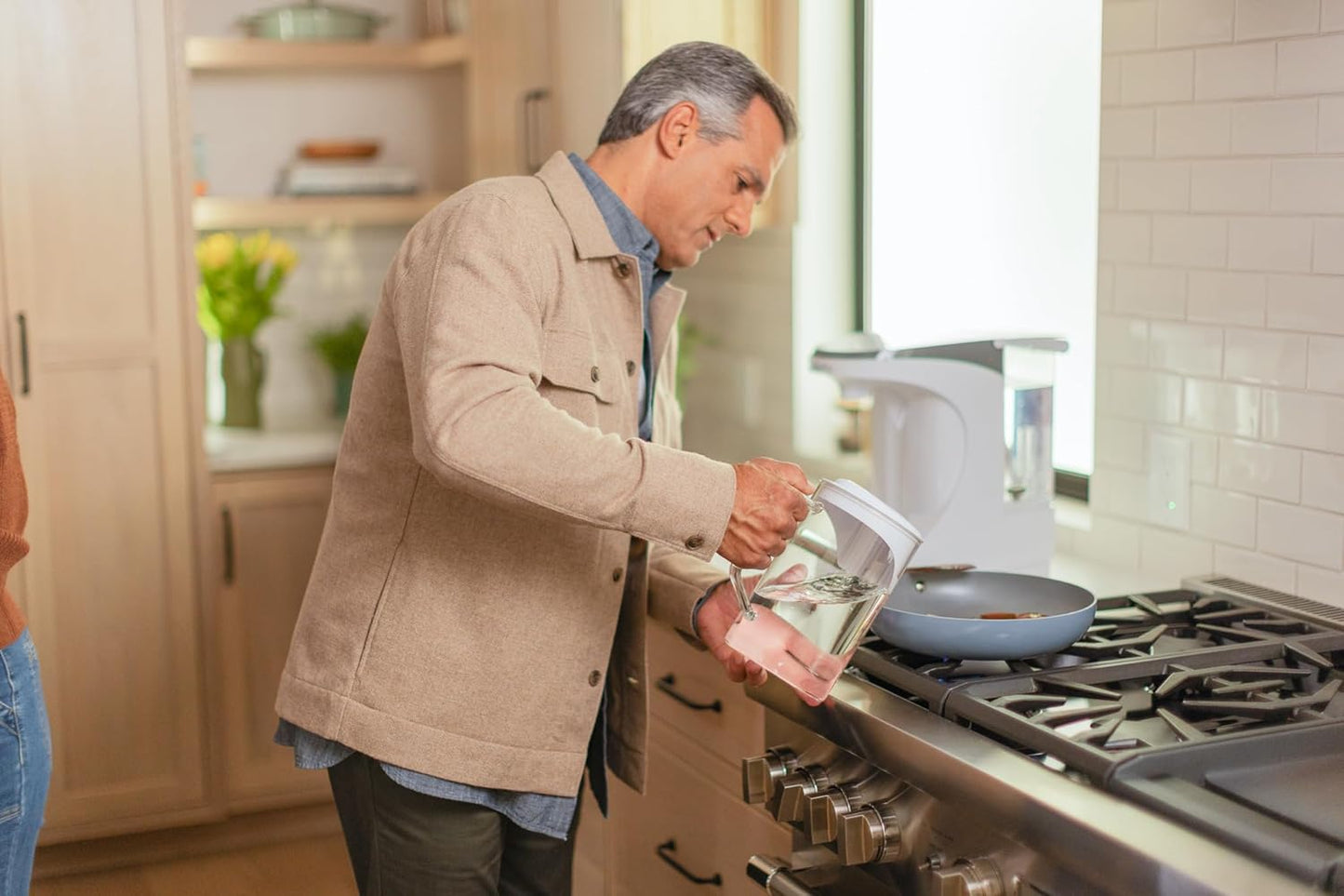 Man in a kitchen poring water to the pan