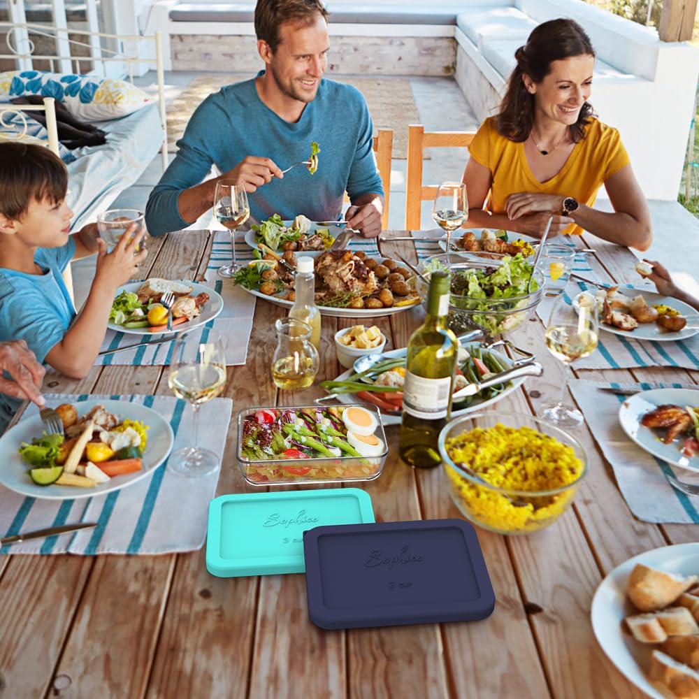 Family enjoying a meal outdoors with plates of food and wine glasses on a wooden table.