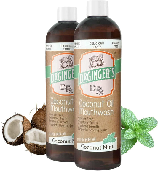 Two bottles of Dr. Ginger's Coconut Oil Mouthwash with coconuts and mint leaves on a white background.