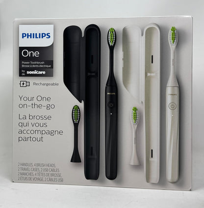 Philips One rechargeable toothbrush set in its original white retail packaging, featuring two black and two white toothbrushes with their charging cases and a travel case.