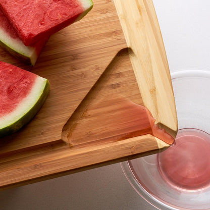Sliced watermelon on a wooden cutting board with a glass of watermelon juice.