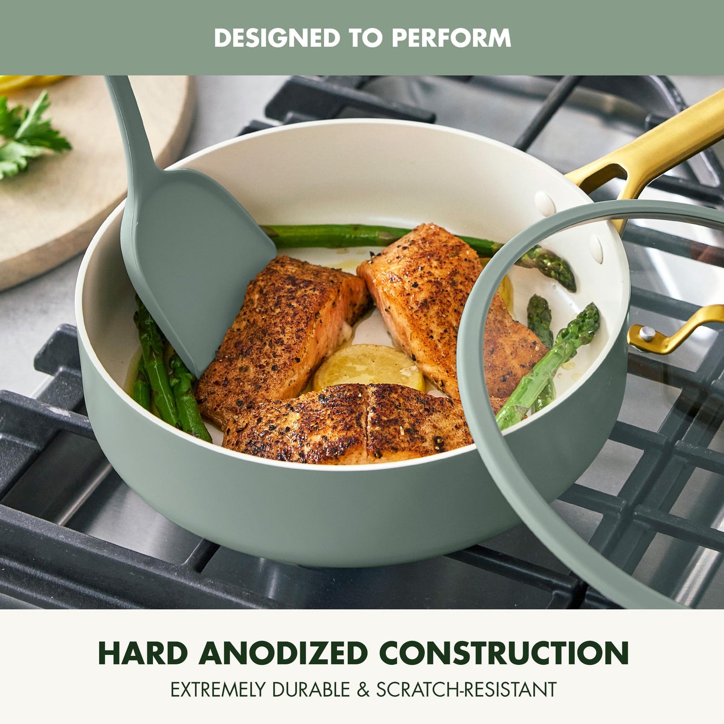 Cooking scene with salmon and asparagus in a green pot on a stove, featuring text about hard anodized construction.