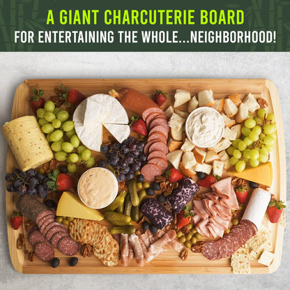 Giant charcuterie board with various meats, cheeses, fruits, and crackers on a wooden board.