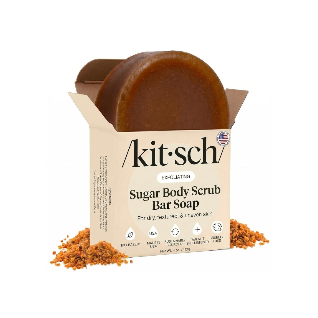 Kit-sch Exfoliating Sugar Body Scrub Bar Soap in an open kraft paper box, with some scrub visible at the top and loose scrub scattered around the base on a white background.
