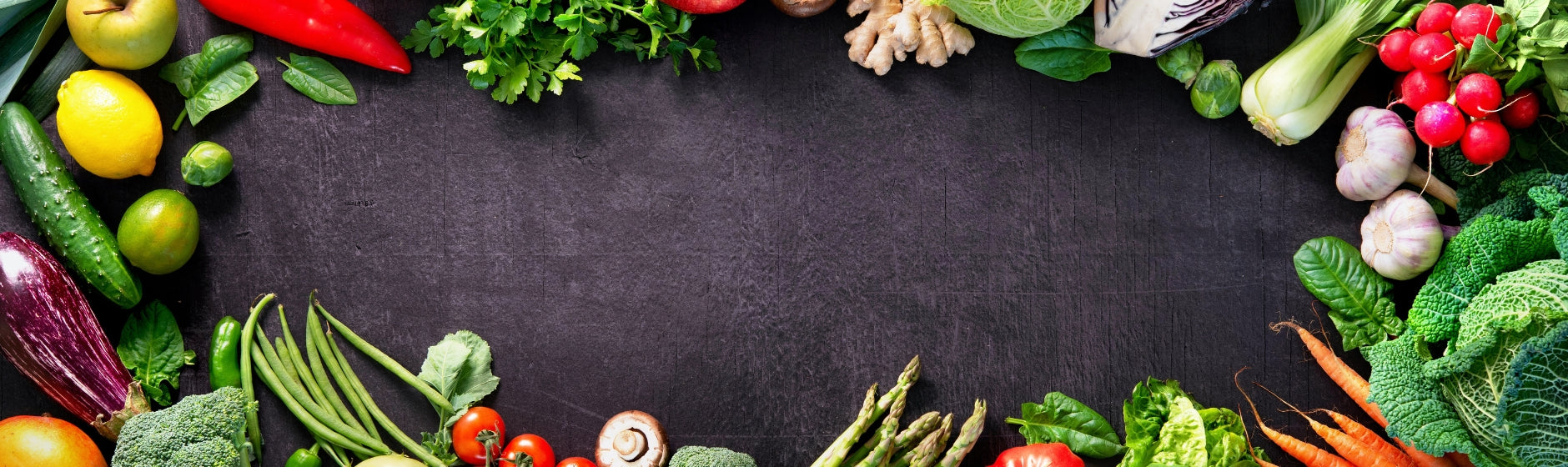 Assorted fresh vegetables arranged around a dark background