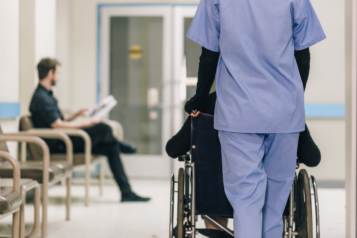 Nurse pushing a man on a wheelchair in the hospital corridor